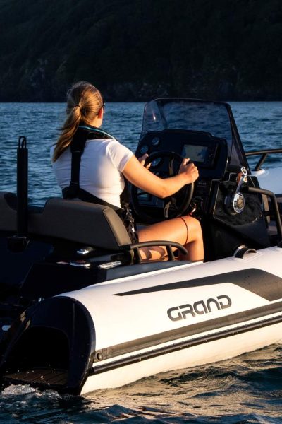 A woman driving the Grand G420 boat at sunset