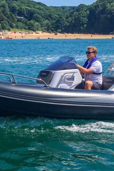 A male driving a Grand G500 boat on the water