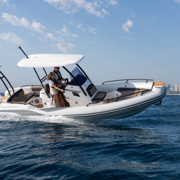Grand G750 RIB boat on the water with a cityscape in the background, two passengers on board