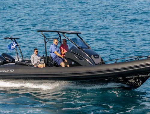 A top selling luxury cruiser boat by Grand - the Grand G850 - on the water with black tubes. Three passengers on board