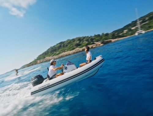 A Grand G340 inflatable watercraft serving as a sports RIB with two passengers on board and a waterskiing passenger in the water behind them