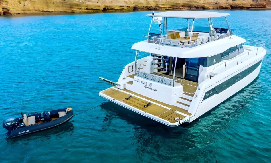 A white yacht with a black boat tender behind it