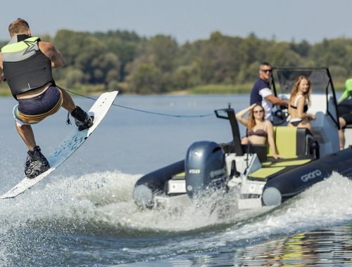 Grand D600 wakeboarding boat with a group on board, and a wakeboarder in the air behind